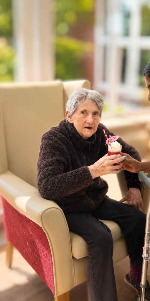 Resident sitting in chair with drink